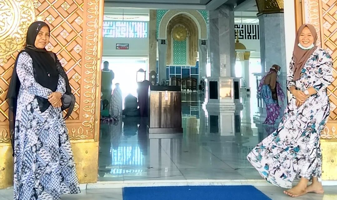 Muliani (kiri) berpose bersama anak mantu saat berada di depan pintu masuk Masjid Al Alam Kendari. Foto: One